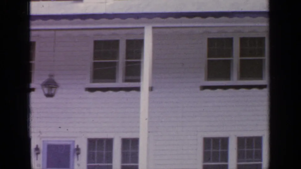 1964 Greenwood Lake home-movie frame showing a white clapboard house facade with multi-pane windows and porch columns.