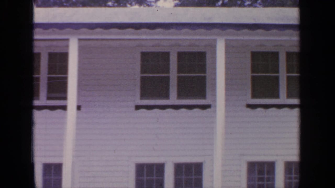 1964 Greenwood Lake frame of a white residential facade with porch roofline, columns, and several windows.