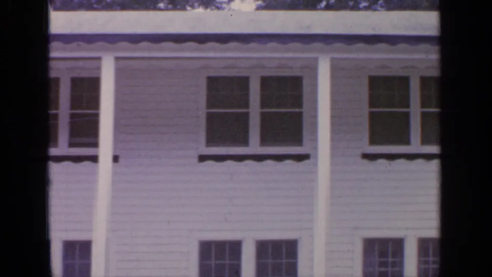 1964 Greenwood Lake frame of a white residential facade with porch roofline, columns, and several windows.