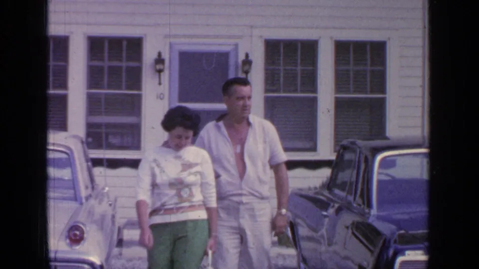 Near the end of the shot, the couple approaches the camera between two parked cars outside the Greenwood Lake house.