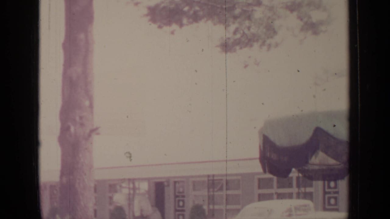 Low building with trees in front and a dark awning or roof detail.