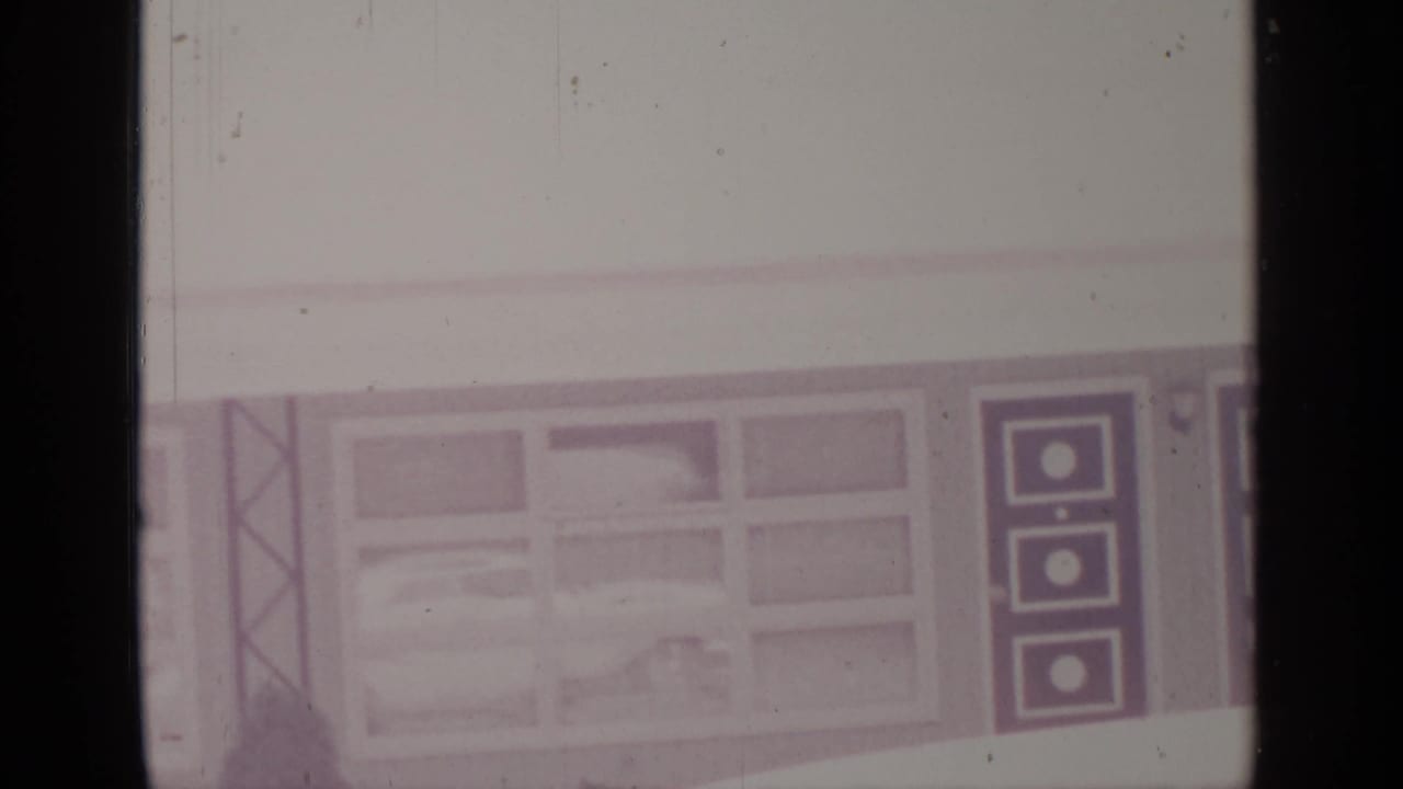 Windowed building wall with a dark patterned door panel and snow in front.