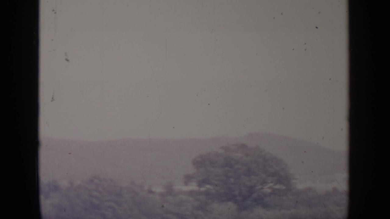Distant hills and treetops seen through a soft, grainy 8mm frame.