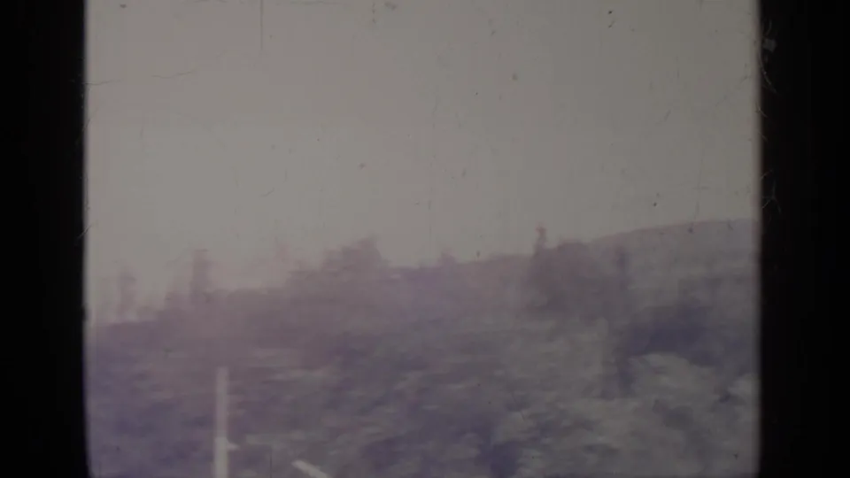 A soft 8mm winter frame from Greenwood Lake showing snow-covered ground, blurred trees, a pale horizon, and dark vertical borders.