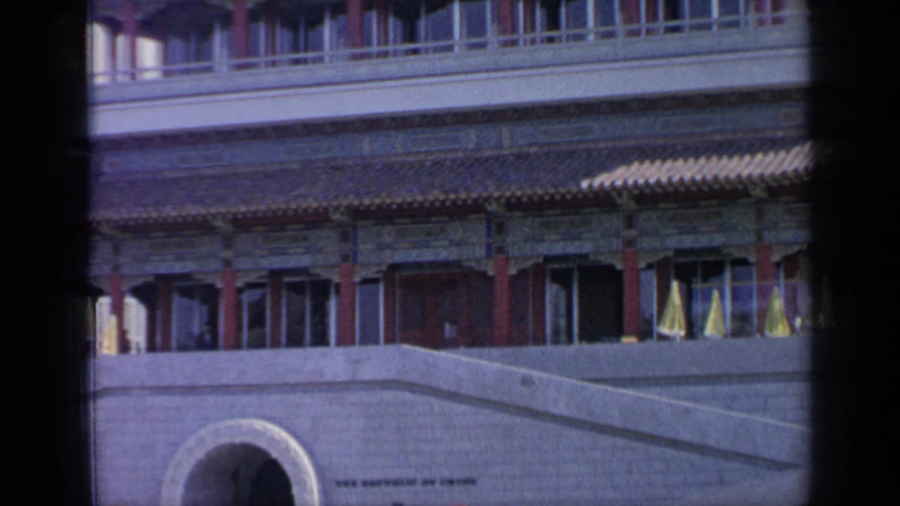 Pavilion wall and tiled roof above a stone arch, with yellow umbrellas along the terrace.