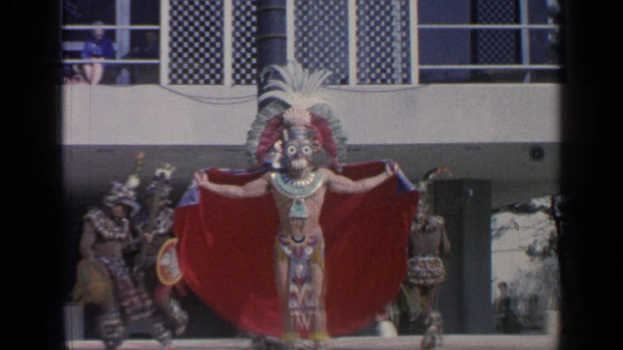 A costumed performer at the 1964 Flushing Meadows World's Fair spreads a red cape, with other dancers and balcony spectators nearby.