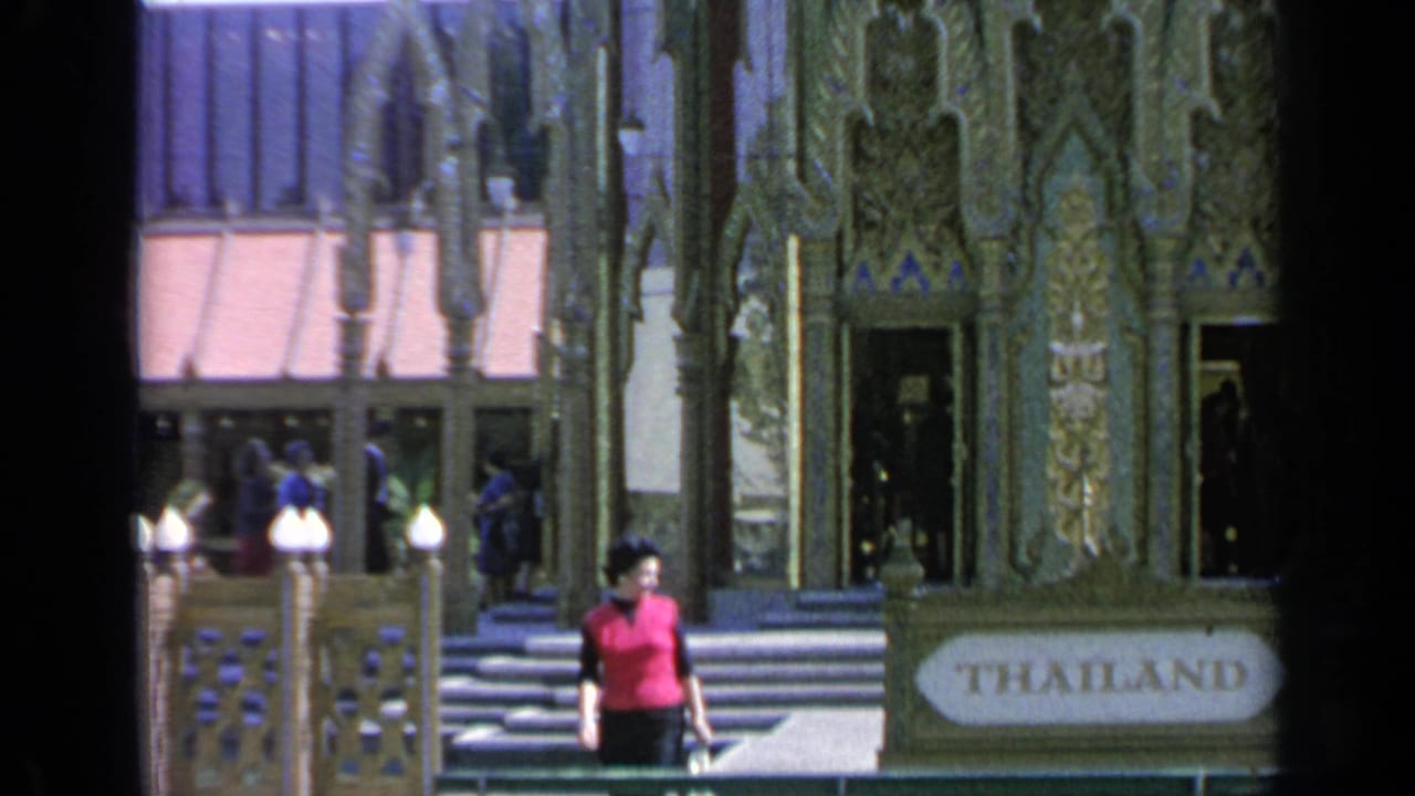 Woman in a red vest near the Thailand Pavilion entrance with visitors on the steps.