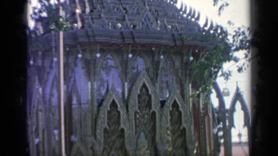 1964 Flushing Meadows home-movie frame focused on the Thai-style pavilion's pointed roof edges and patterned wall surfaces.