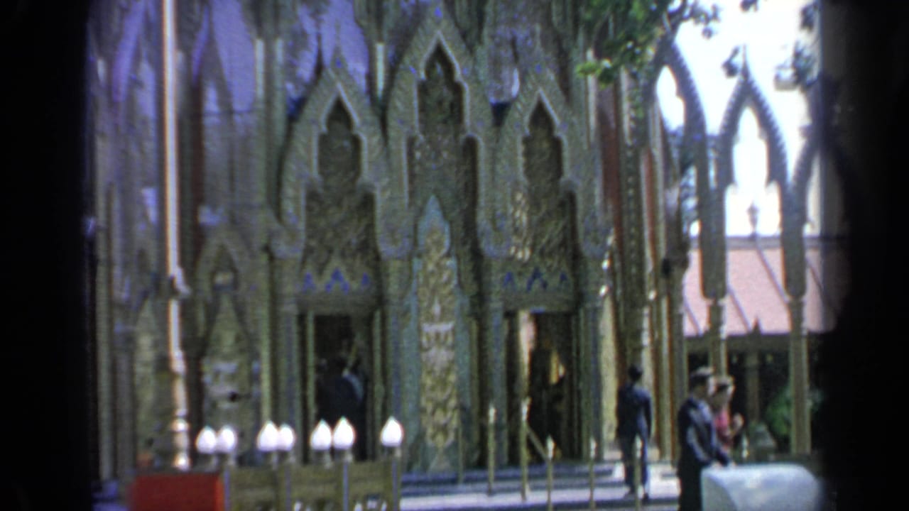 Ornate Thai pavilion entrance with visitors near carved gold facade.