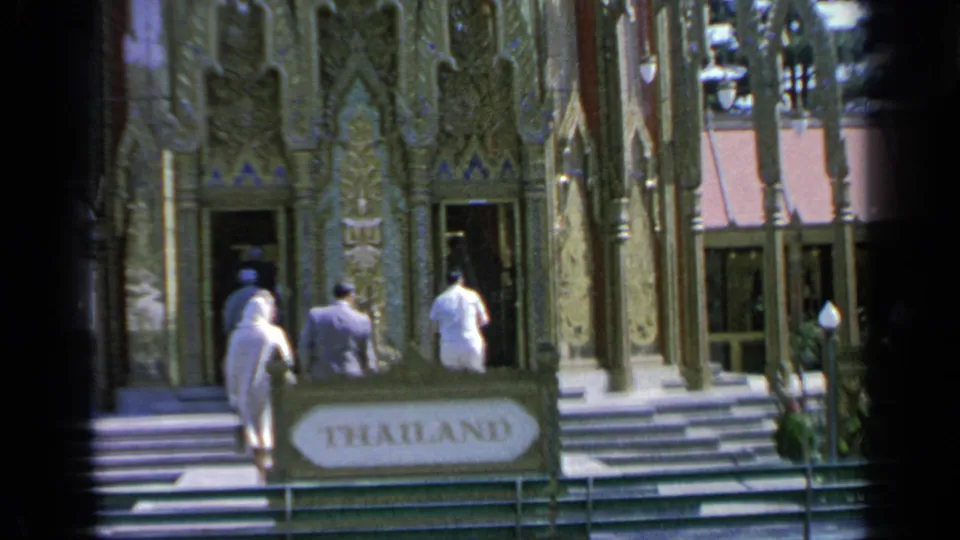 1964 Flushing Meadows fair visitors approach the Thailand pavilion, with an ornate facade and foreground THAILAND sign visible.