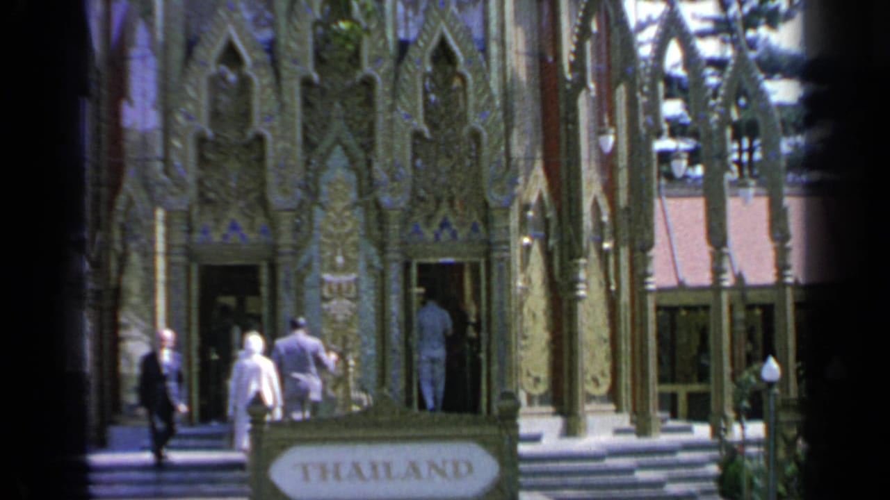 Visitors near the ornate Thailand Pavilion entrance with a THAILAND sign in front.