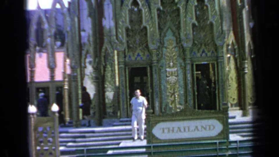 A man in white walks toward the camera from the Thailand Pavilion steps at the 1964 Flushing Meadows World's Fair.