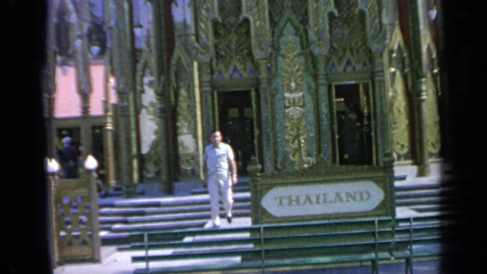 The Thailand Pavilion sign and ornate entrance remain visible as a man in white descends the steps during the 1964 fair.