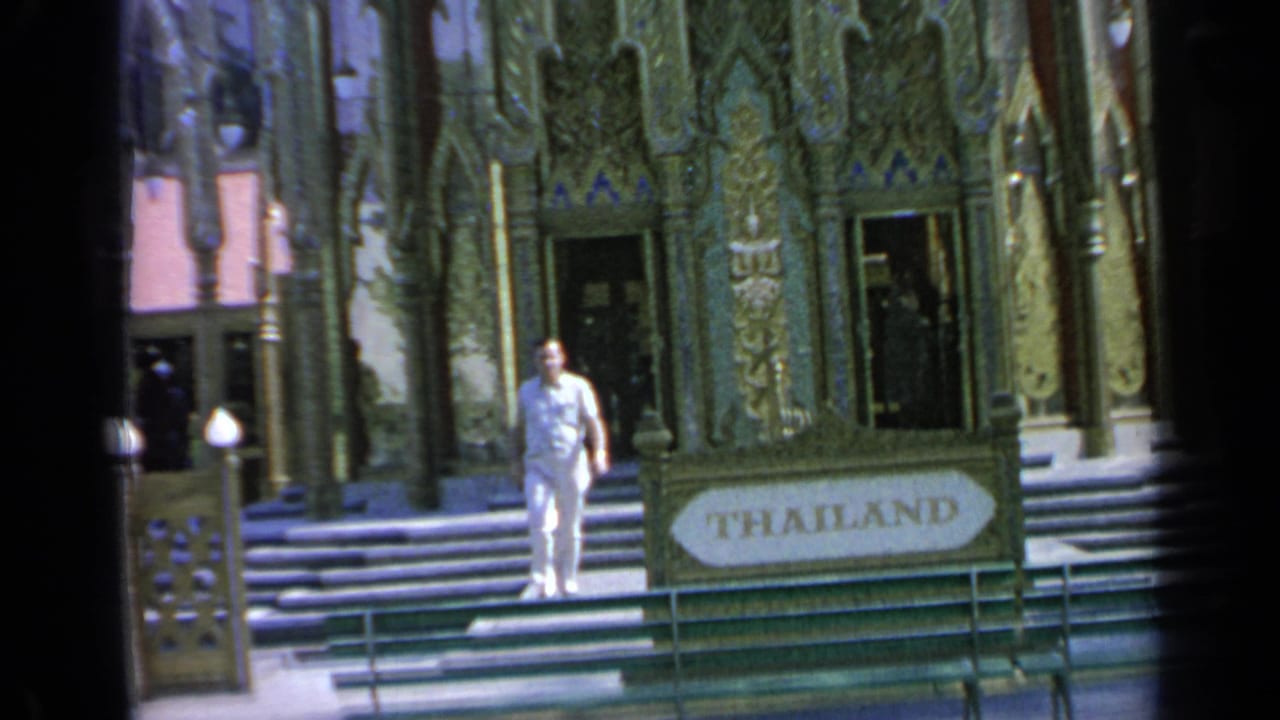 Man in light clothing walks near the Thailand Pavilion entrance and sign.
