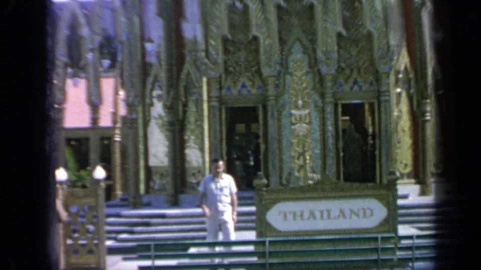 1964 Flushing Meadows frame showing a visitor near the Thailand Pavilion sign, railings, steps, and carved-looking facade.