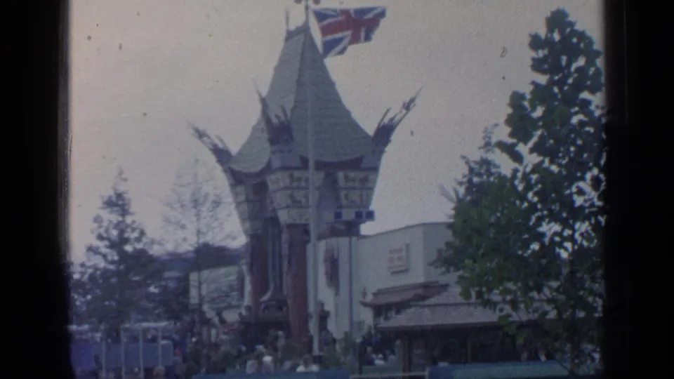 World's Fair pavilion at Flushing Meadows with a Union Jack flag, trees, and small groups of visitors near the entrance.