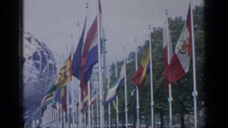 International flags stand in rows at Flushing Meadows, with the Unisphere partly visible in the background.