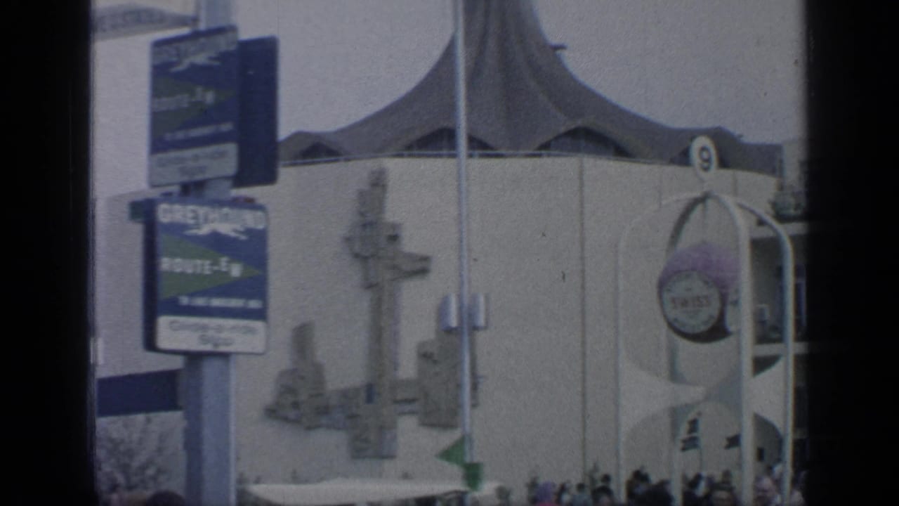 Fairground signs and tent-roof building with visitors near the entrance.