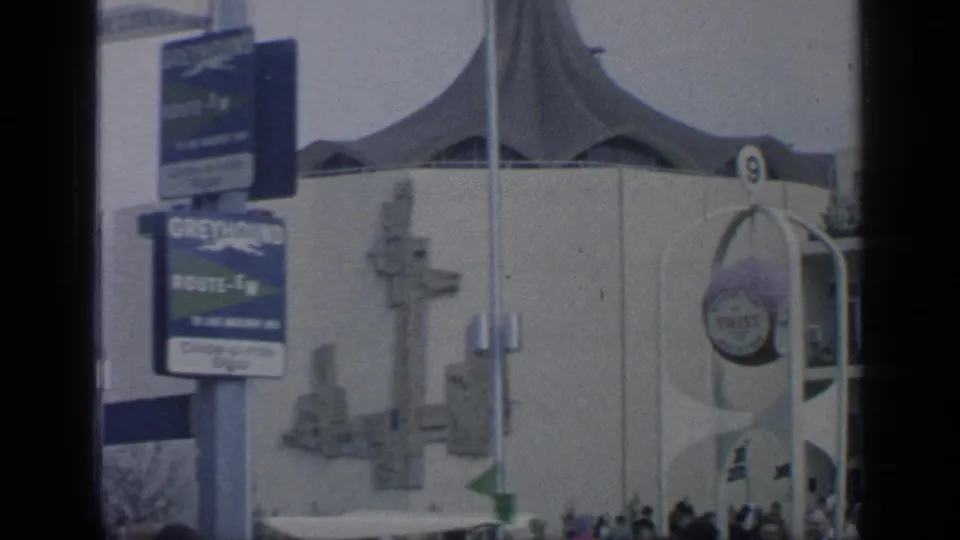 1964 Flushing Meadows fairground view with Greyhound Route-EW signage, a tent-like roof structure, and visitors near an entrance marked 9.