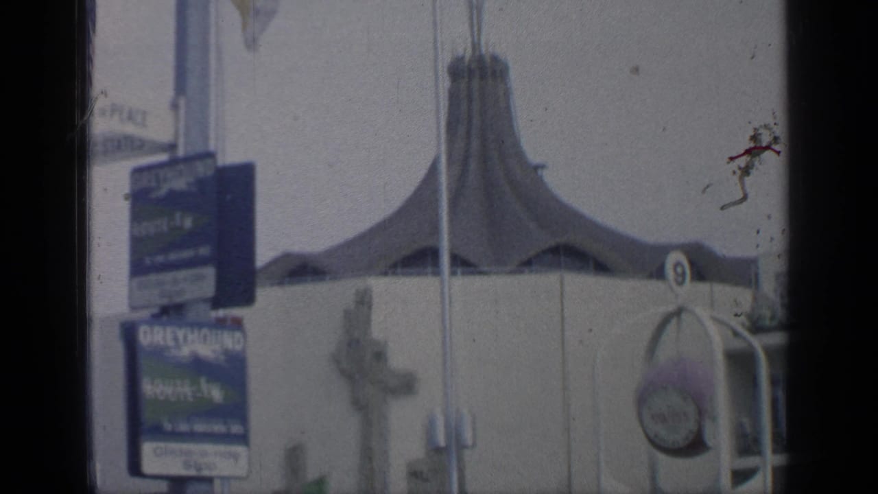 Tent-roof fair building with route signs, poles, and entrance detail.