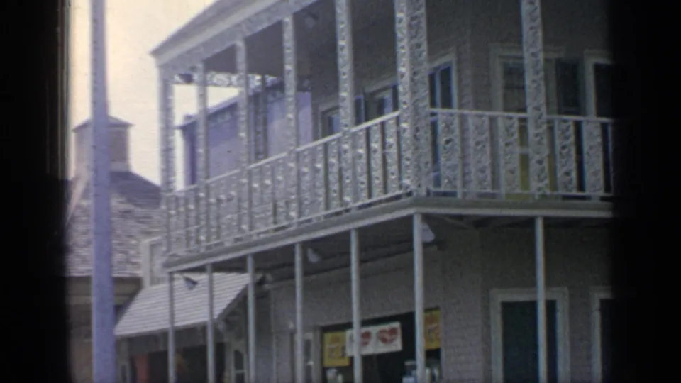 Visitor-shot 1964 Flushing Meadows exterior with decorated balcony railings, upper windows, vertical supports, and small storefront signs below.
