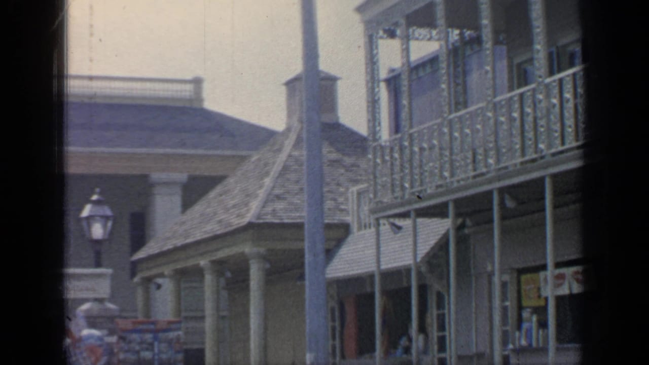Historic-style facade with balcony, lamppost, awning, and souvenir area below.