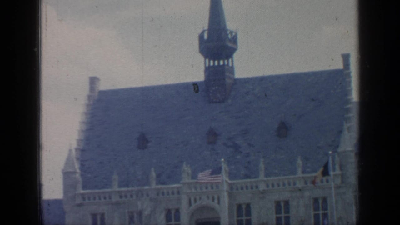 Steep slate roof and tall spire above a stone building facade.