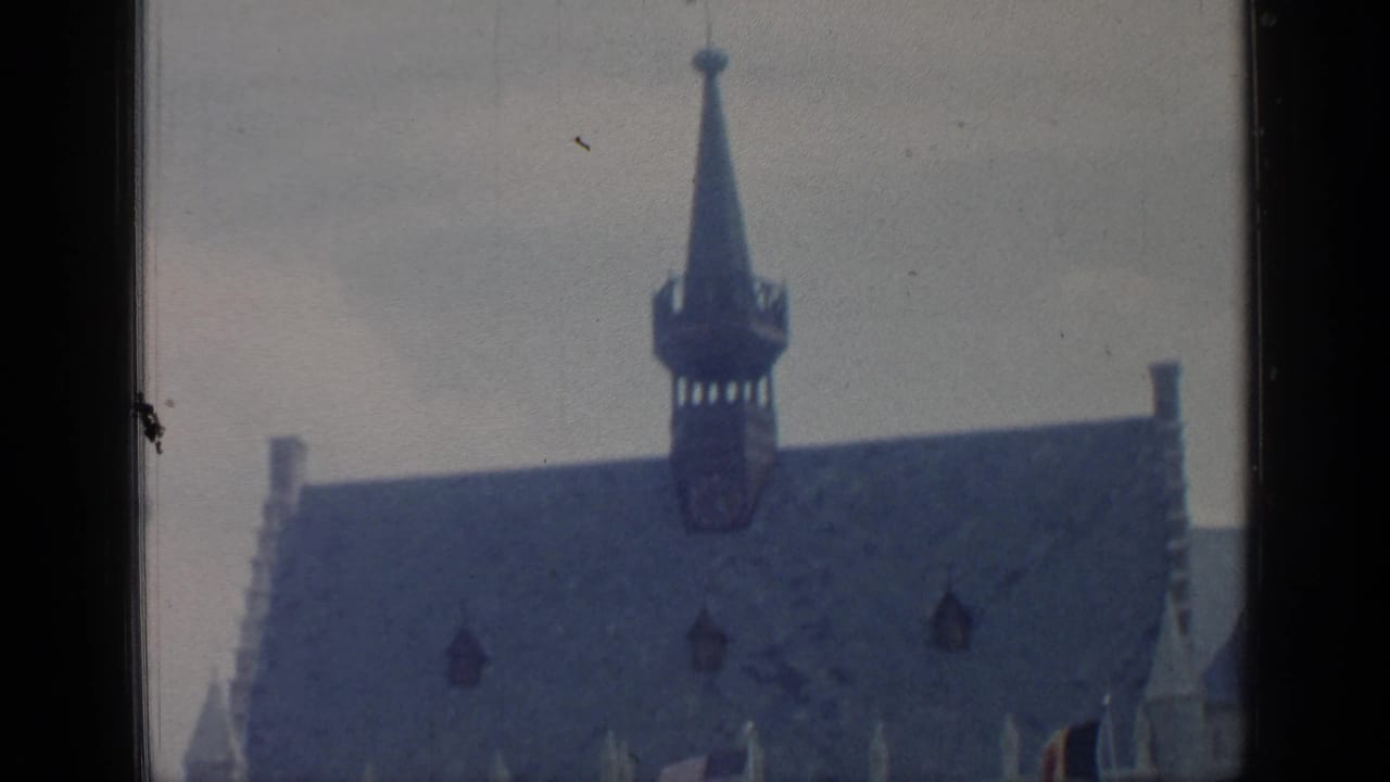 Upper portion of a steep-roofed building with a central spire.