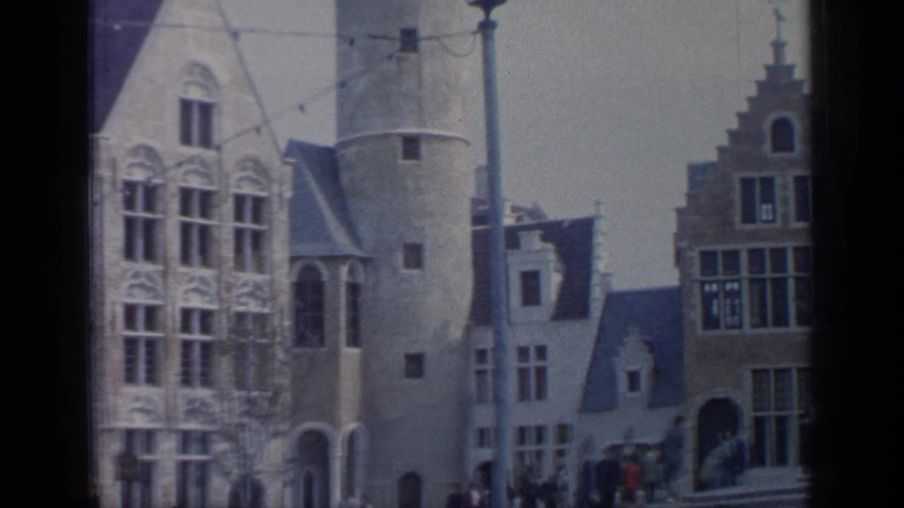 Round tower, ornate windows, stepped-gable building, and distant pedestrians in a plaza.