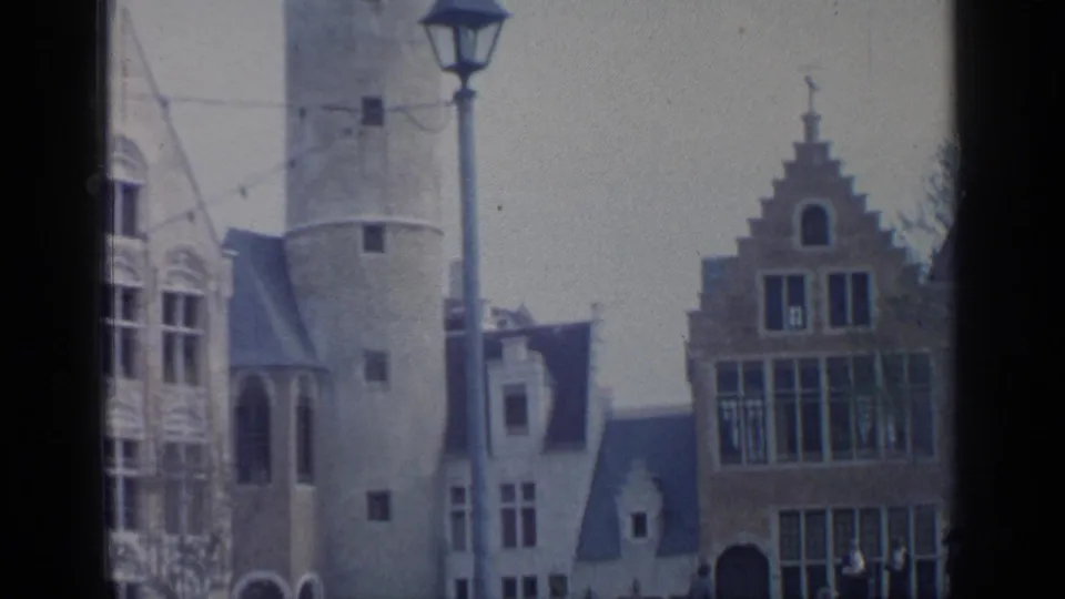 1964 Flushing Meadows exterior with a pale tower, historicist facades, a street lamp, and small pedestrian figures.