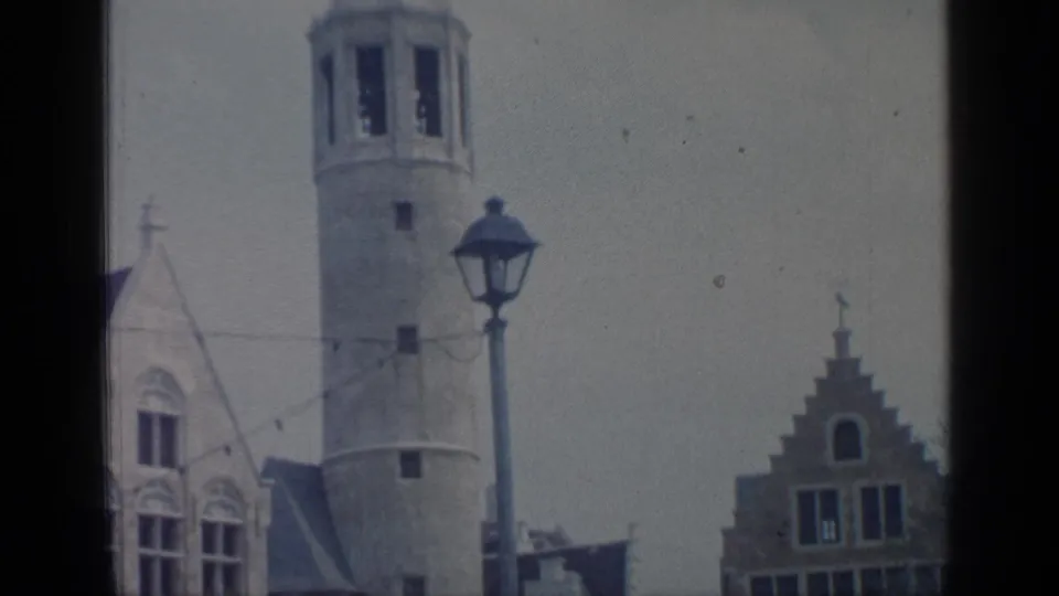 1964 Flushing Meadows footage ending on a tower, street lamp, and stepped-gable facade under an overcast sky.