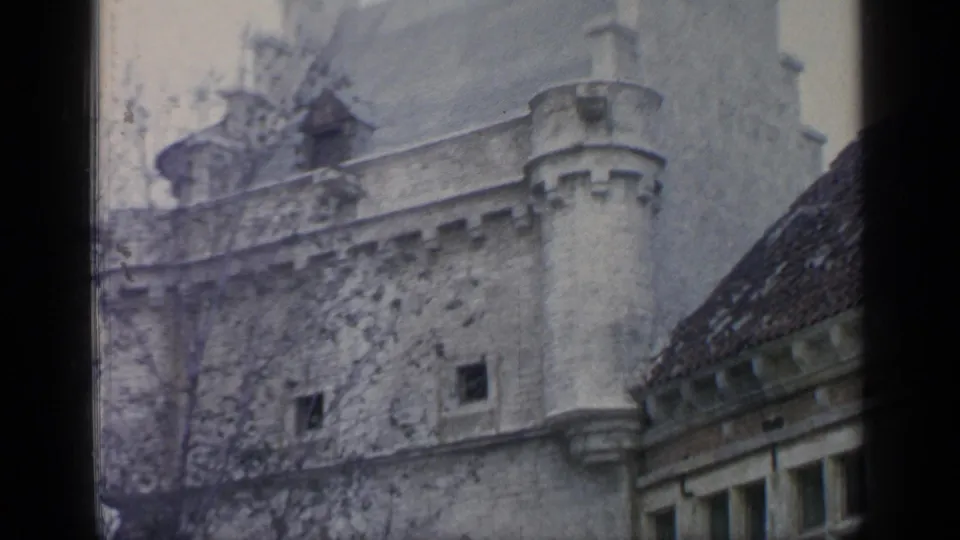 1964 8mm frame showing a stone turret-like wall and adjacent roofline at the themed World's Fair village set.