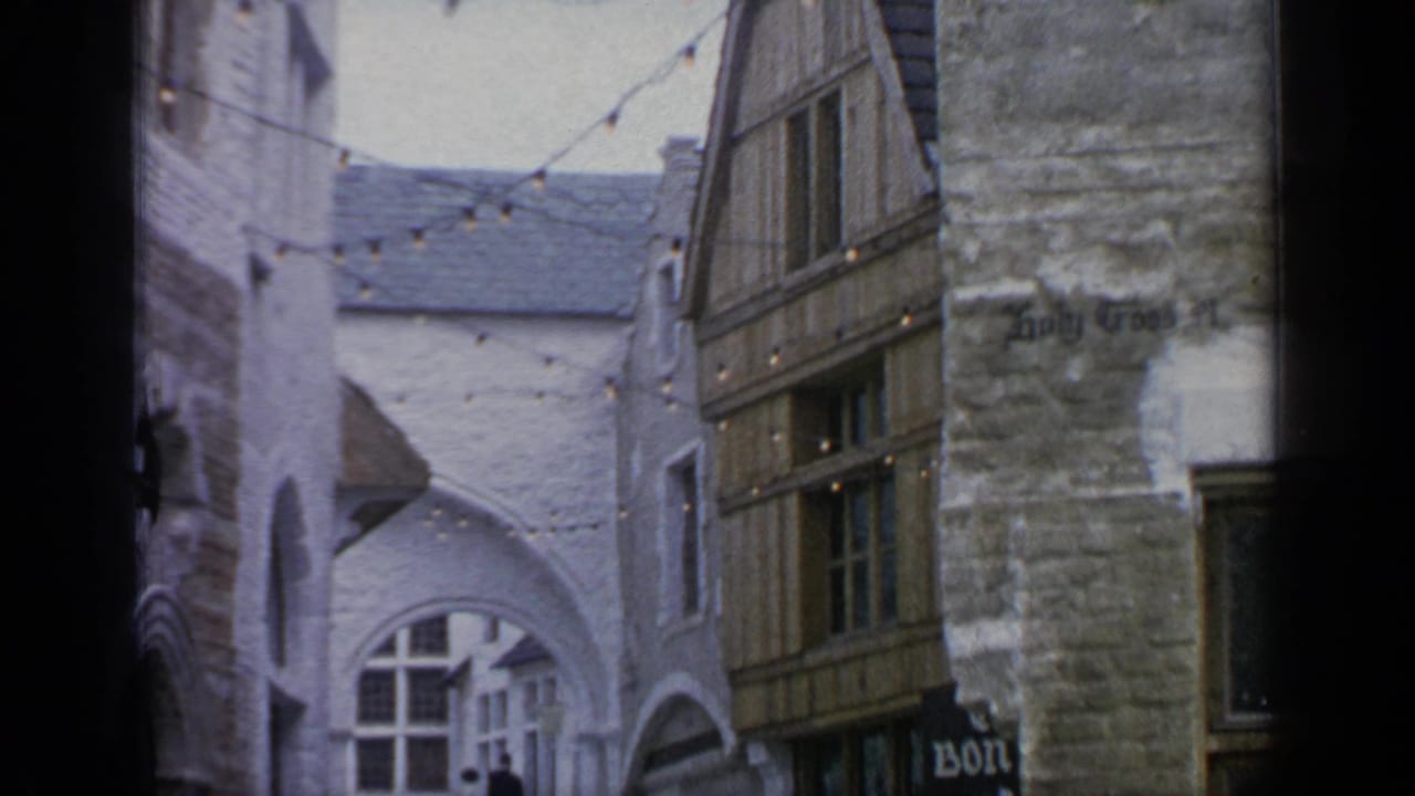 Narrow alley with stone and timber-style buildings, string lights, and a partially visible sign.