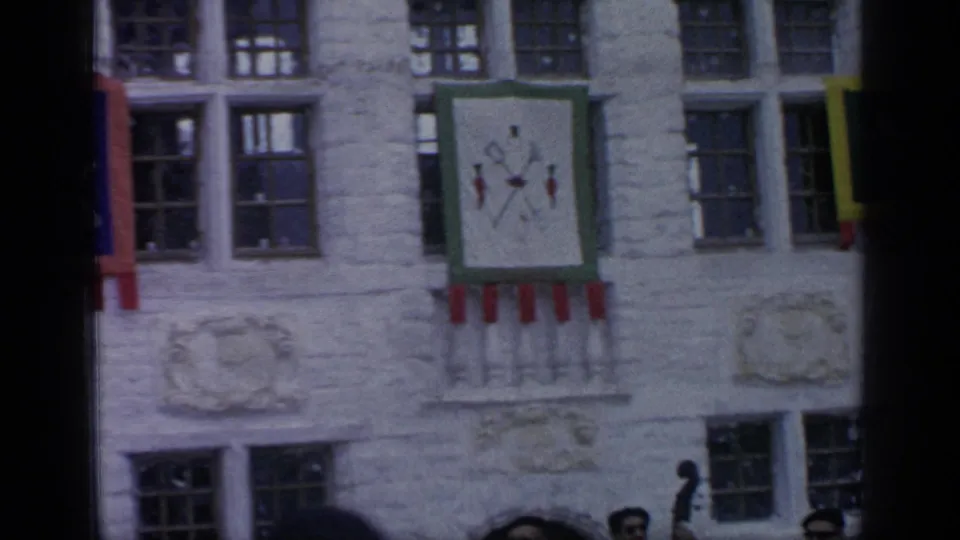 1964 Flushing Meadows frame showing banners and windows on a themed stone facade, with the band partly visible at the bottom.