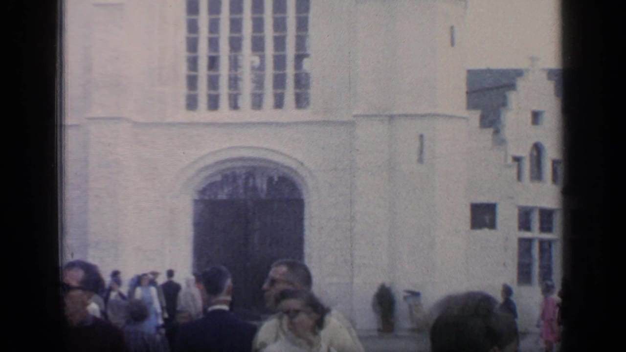 Visitors standing near a white Gothic-style building entrance with tall windows above.