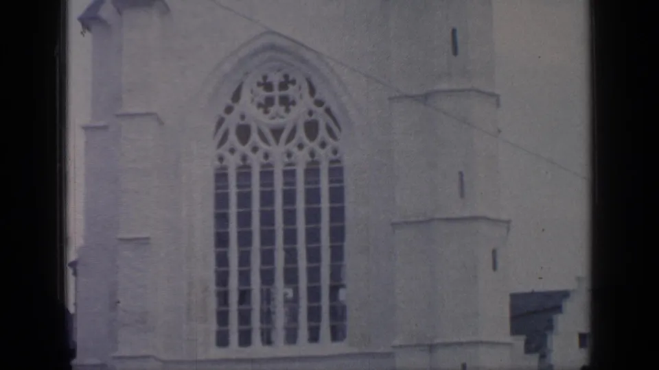 1964 Flushing Meadows 8mm still showing ornate tracery and vertical panes on a white Gothic-style building facade.