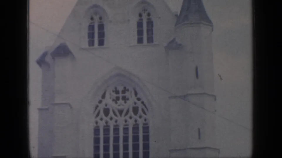 1964 Flushing Meadows frame showing the upper facade, arched window, small upper windows, and roofline of the white building.