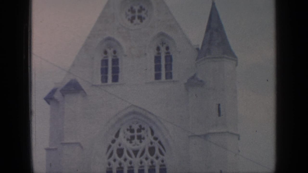 White Gothic-style church facade with arched windows and a pointed side spire.