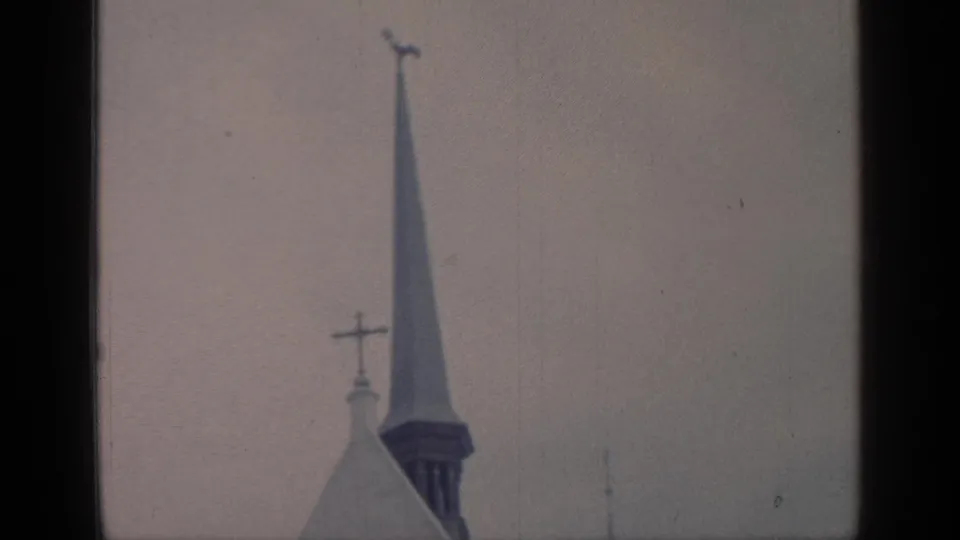 1964 8mm frame showing a church steeple and cross forms against an overcast sky in the Flushing Meadows reel.