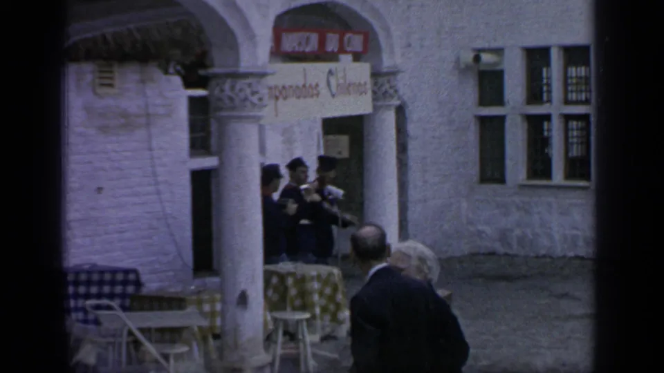 Visitors stand near a building facade with arches, tables, and a readable Oriental Fudge sign in the 1964 Flushing Meadows footage.