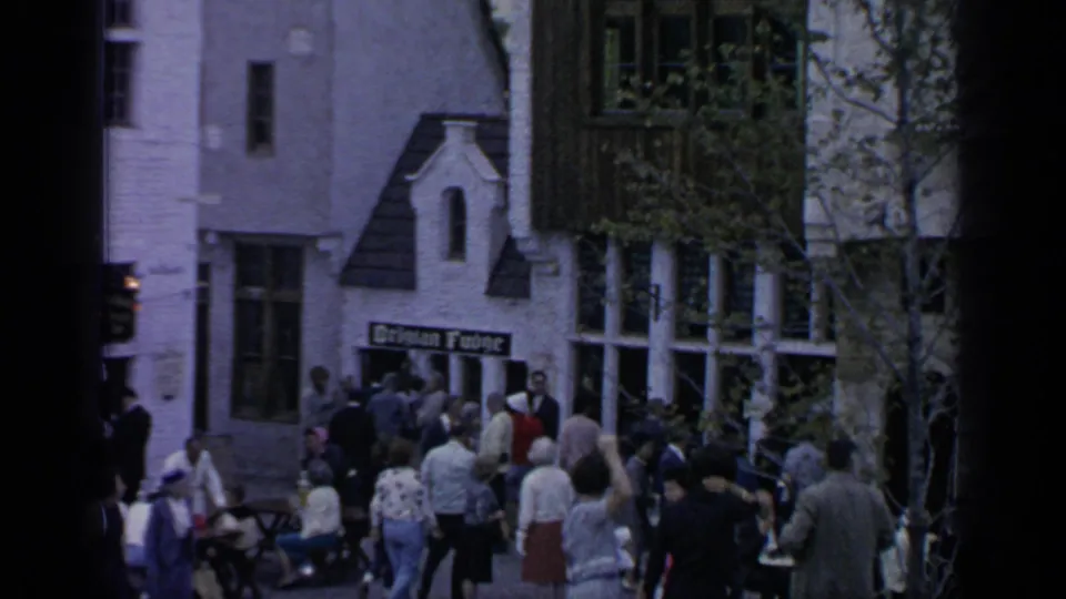 Visitors gather outside a fair building in Flushing Meadows, with a sign appearing to read German House above the entrance.