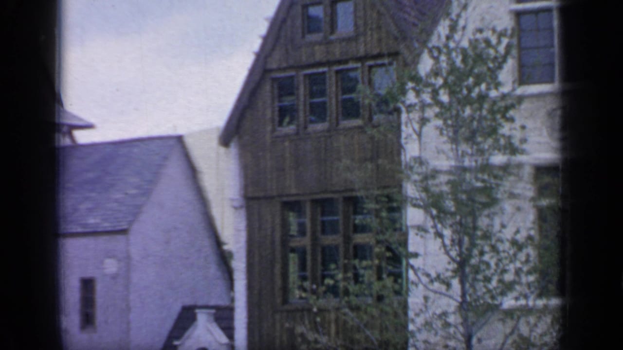 1964 Flushing Meadows visitor footage showing half-timbered and white-walled village-style buildings framed by dark film edges.