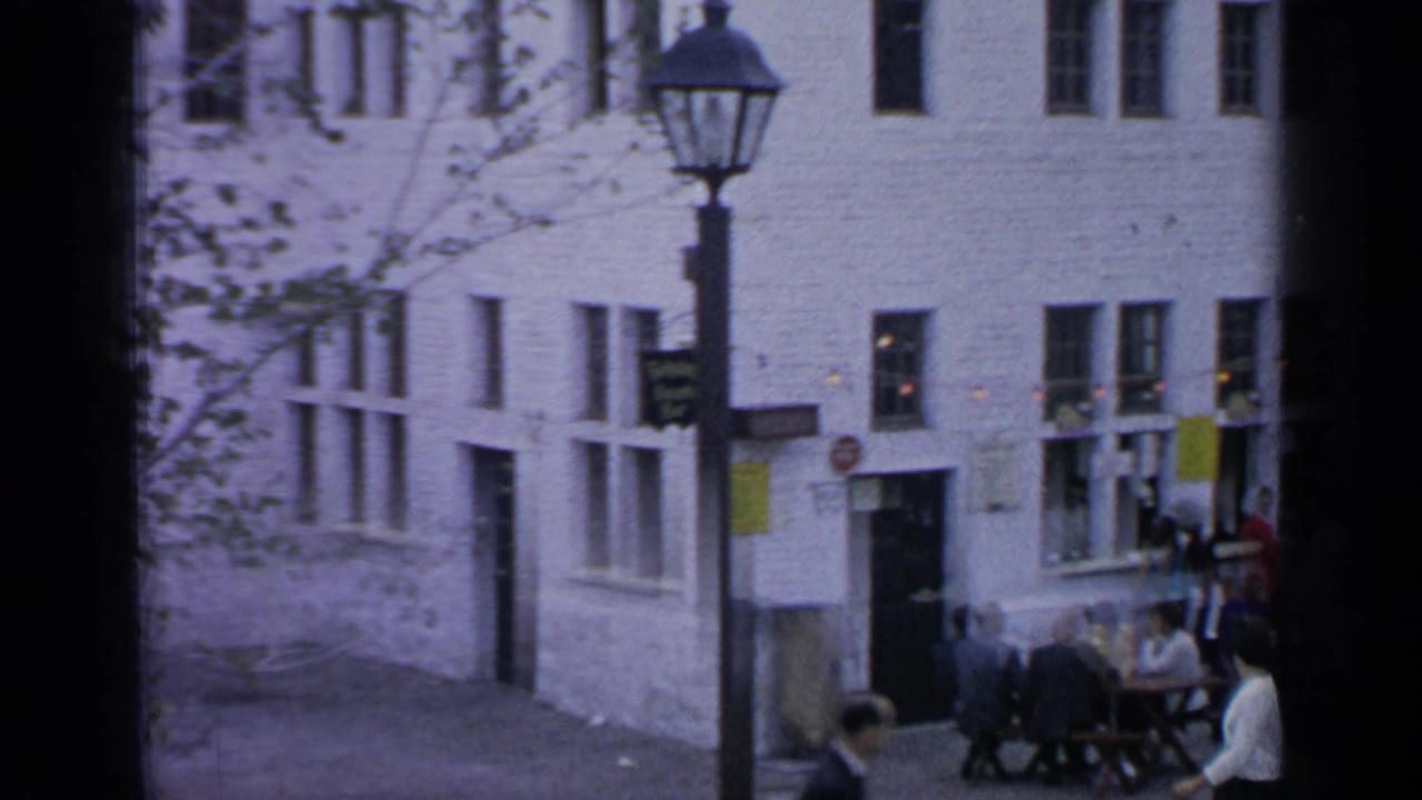 White brick facade, streetlamp, pedestrians, and outdoor seating in a pedestrian area.