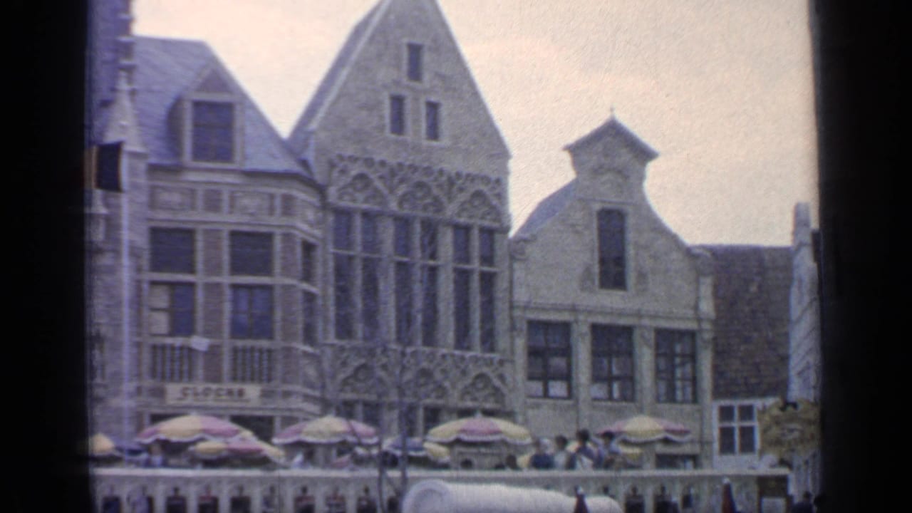Historic-style buildings and cafe umbrellas with people in the plaza.