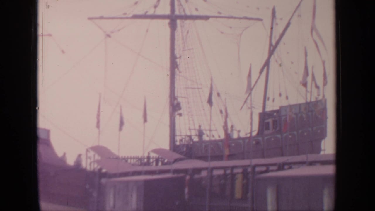 1964 Flushing Meadows frame of a docked period-style vessel with deck visitors, rigging, and small flags.