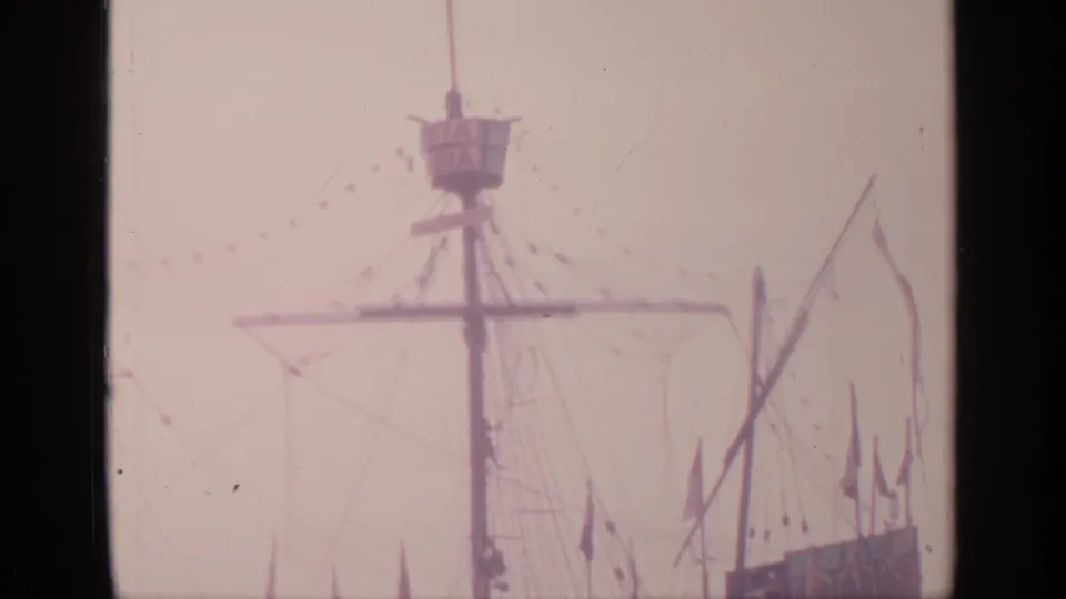 Cropped 8mm view of the 1964 World's Fair ship model, with mast rigging and flags silhouetted in haze.
