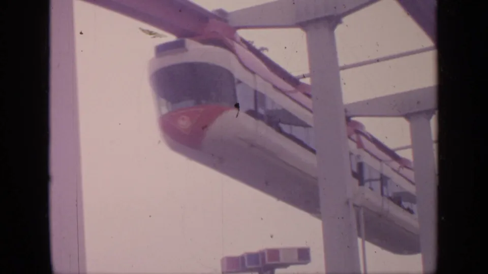 1964 Flushing Meadows frame showing the tramway car aligned with the elevated track and white structural supports.