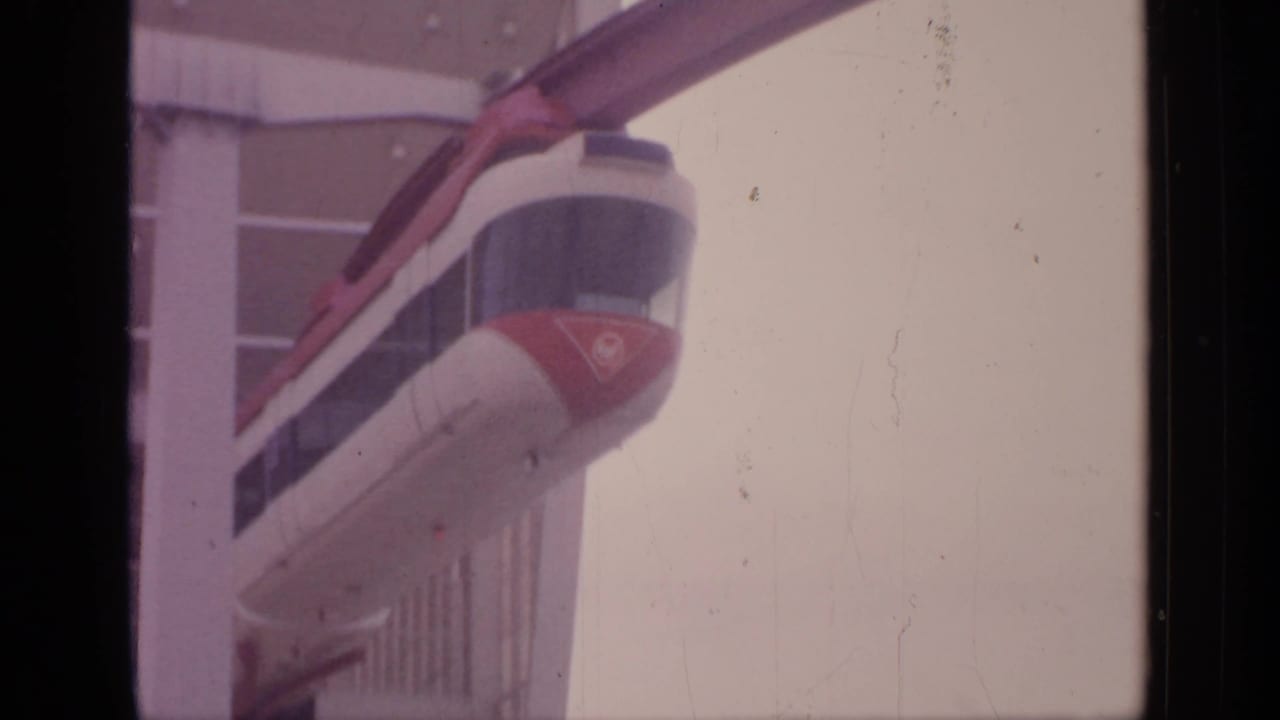 Monorail nose and guideway aligned with a glass station facade.