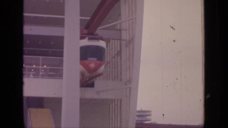 1964 Flushing Meadows footage showing a red and white cable car near a modern multi-level structure.