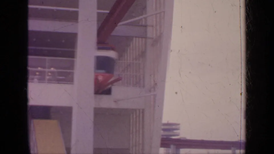 A red and white cable car appears behind vertical columns in the 1964 Flushing Meadows scene.